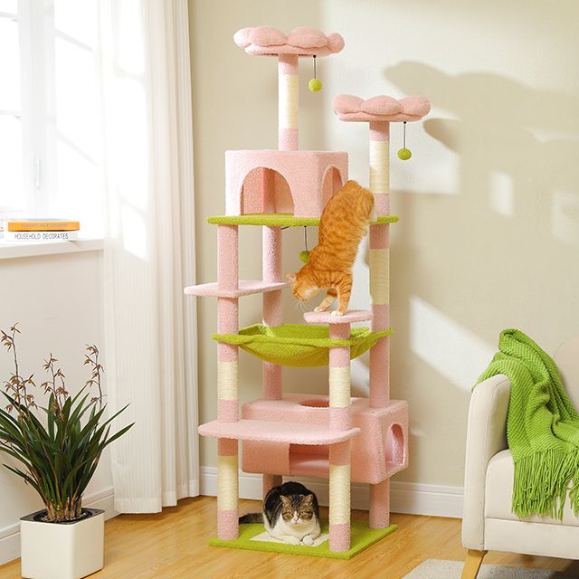 Pink and green cat tree with two cats on a light-colored floor.