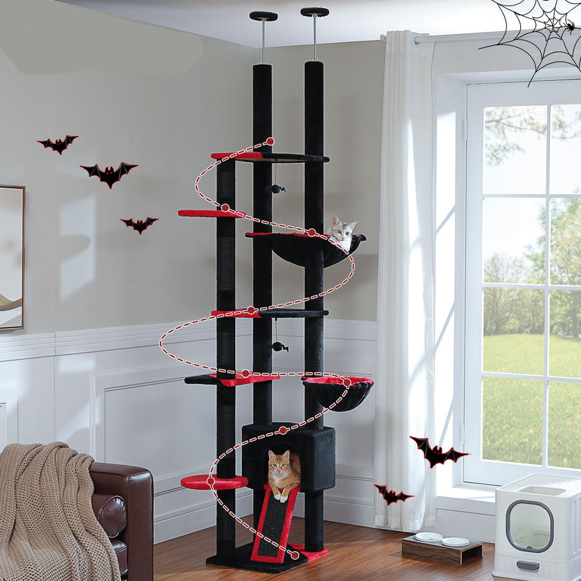 Black and red cat tree with two cats on a white wall with Halloween decorations.