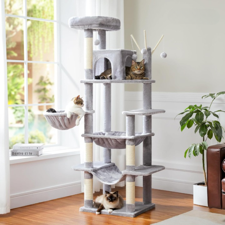 Cat tree with multiple levels and a cat sitting on one of the platforms in a room with a window and plant.