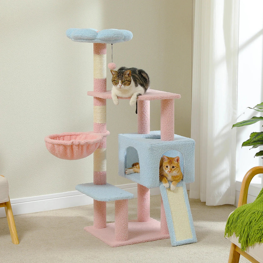 Cat tree with multiple levels and a cat sitting on top in a room with light-colored walls and a plant.